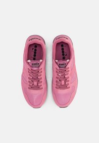 Pink athletic shoes with mesh and suede materials, rounded toe, thick rubber sole, and matching laces; features logo on tongue and side.