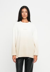 Jasno beżowy, oversize'owy sweatshirt z okrągłym dekoltem i długimi rękawami. Zawiera subtelne logo na środku. Gładka tekstura, luźny krój.