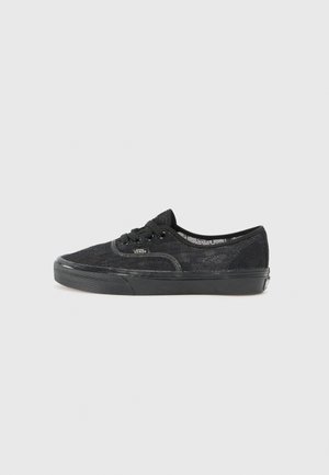 Black lace sneaker with black rubber sole, round toe, and black laces. Features a textured lace overlay and subtle branding on the side.