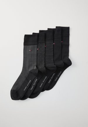 Schwarzes Socken-Set mit verschiedenen Texturen: Fischgrätenmuster, dezente Pünktchen und einfarbig, mit auffälligem Logo-Detail an den Bündchen.