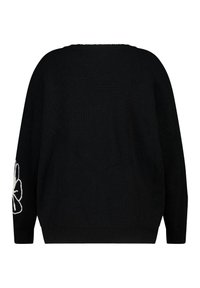 Zwarte gebreide trui met een losse pasvorm, geribbelde textuur en lange mouwen. Gedetailleerd met een witte geborduurde bloem op de linker mouw.