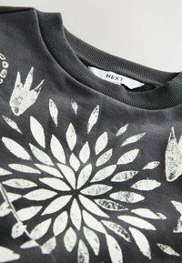 Mørkegrå sweatshirt med hvid blomsterprint og ribbet krave, viser brandmærket "NEXT" indeni i halsudskæringen.