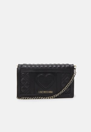Czarny pikowany portfel Love Moschino z detalem serca i złotym łańcuszkiem na jednolitym białym tle.