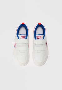 Bijele Reebok tenisice s plavim unutarnjim oblogama i crvenim logotipom, s dva čičak remena i crvenim povlačnim trakama na bijeloj pozadini.