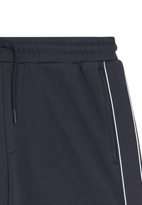 Marineblauwe sweatpants met elastische tailleband, een trekkoord en witte zijstrepen. Zachte textuur met een relaxte pasvorm. Geen zichtbare zakken.