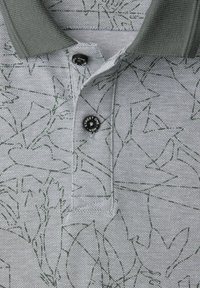 Polo gris clair avec motifs abstraits en lignes vert foncé, col vert foncé et deux boutons noirs étiquetés "STREET ONE MEN".