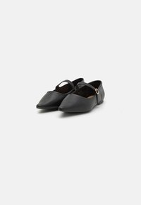 Mustad nahast madalad jalanõud terava varbaga, millel on kitsas pahkluu rihm ja ringikujuline aksessuaar. Sile tekstuur ja minimalism.