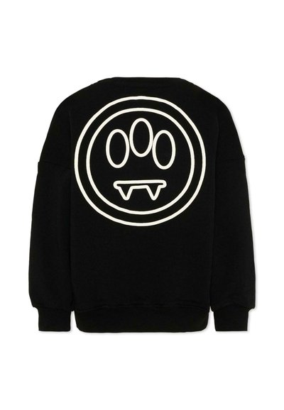 Sweat-shirt noir avec grand emblème circulaire blanc au dos, présentant trois ovales verticaux au-dessus de deux formes de crocs pointus à l'intérieur d'un double contour.