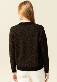 Brun leopardmönstrad tröja med svart ribbad krage och ärmslut, med långa ärmar och en avslappnad passform. Texturerat tyg förbättrar designen.