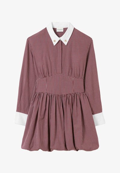 Abito a quadri rosso e bianco con gonna plissettata, caratterizzato da un colletto bianco e bottoni dorati all'altezza del collo. Maniche lunghe con polsini bianchi.