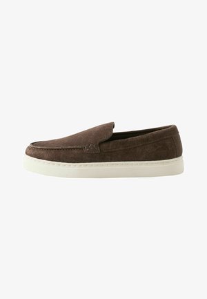 Brun ruskind slip-on sko med hvid gummisål, fladt design og enkel syning langs den øvre kant.