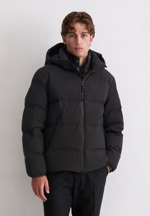 Veste rembourrée noire avec capuche, fermeture éclair sur le devant et deux poches latérales. Présente un design matelassé avec une texture lisse et un marquage minimal.