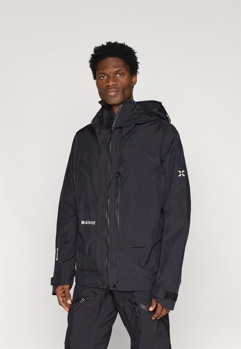 Czarna wodoodporna kurtka z kapturem, z zamkiem błyskawicznym z przodu i kieszeniami, elastycznymi mankietami oraz logo na piersi. Gładka tekstura.