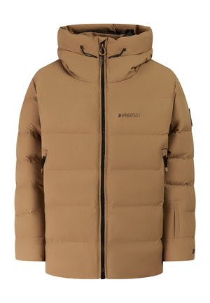 Jongere draagt een beige gewatteerde jas, zwarte broek, zwarte handschoenen, zwarte laarzen en een zwarte muts, staand tegen een effen achtergrond.