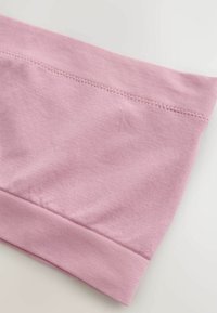 Tissu rose doux avec ceinture élastique côtelée et ourlet, montrant une texture lisse et des coutures soignées sur une surface plane.