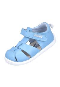 Sandal de punta cerrada de color azul claro, fabricada en material sintético, con correas cruzadas, una correa de velcro y una suela de goma blanca.