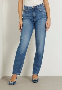 Jasnoniebieskie jeansy z wysokim stanem i prostymi nogawkami, z zapięciem na guzik i klasycznym pięciopocketowym wzorem, ukazujące wypłowiały wygląd denimu.