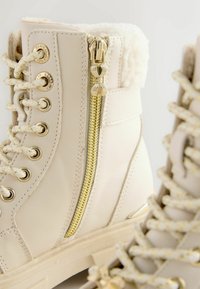 Witte faux leren laarzen met een gestructureerde kraag, gouden ritsdetails en beige veters. Voorzien van metalen oogjes en een chunky zool.