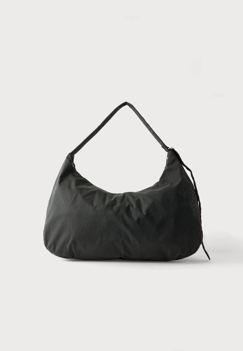 Sac d’épaule en tissu noir doux avec une bandoulière simple et une texture légèrement froissée sur un fond clair uni.