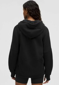 Czarna bluza z kapturem wykonana z miękkiego materiału, z dużym kapturem, długimi rękawami i wyraźnymi detalami szwów. Z tyłu znajduje się akcent z logo.