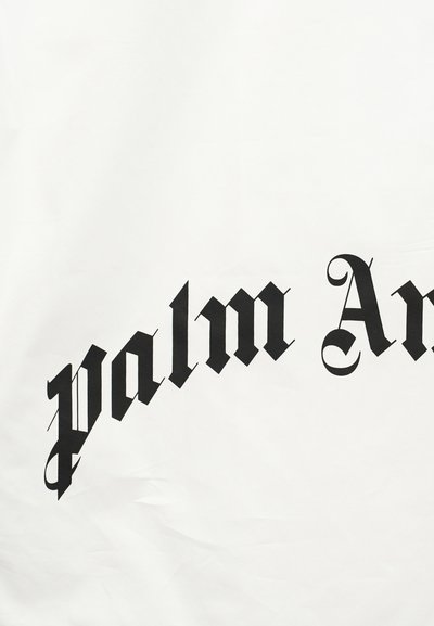 Μαύρο γοτθικό κείμενο που γράφει «palm An» σε λευκό υφασμάτινο φόντο, μέρος μεγαλύτερης τυπωμένης φράσης ή ονόματος μάρκας.