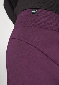 Puma lila sweatshirtbyxor har en mjuk textur och ribbad midja. Nära bild visar färgrikedom och sömnadsdetaljer.