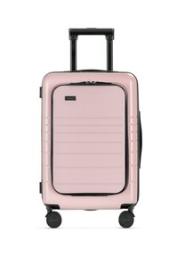 Różowa walizka twarda z poziomymi rowkami, czarnymi akcentami, wysuwanym uchwytem oraz czterema obrotowymi kółkami, co zapewnia łatwą mobilność.