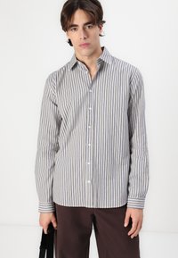 Gestreiftes Button-Up-Hemd in Hellgrau und Marineblau. Hergestellt aus Baumwolle, mit langen Ärmeln, einem Kragen und einem geraden Saum mit geknöpften Manschetten.