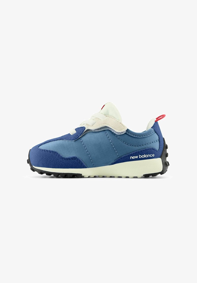 Zapatilla New Balance en azul y beige con cordones blancos, pestaña trasera roja y suela texturizada negra mostrada en perfil lateral.