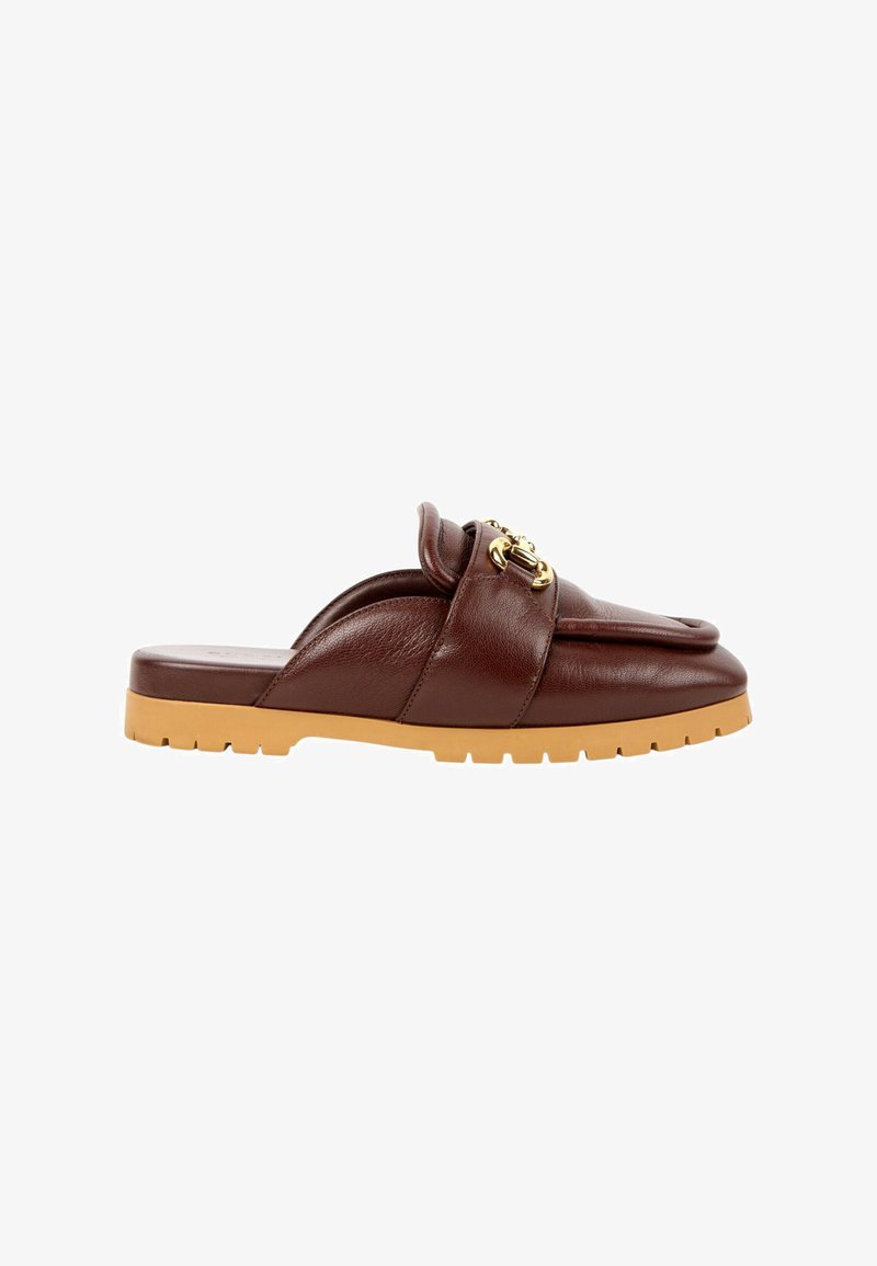 Mocassin marron en cuir à enfiler avec une semelle en caoutchouc beige et un détail chaîne dorée dessus, vu de côté sur fond blanc.