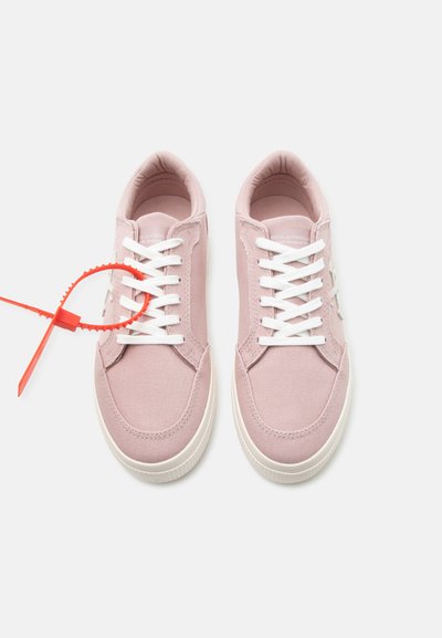 Ζευγάρι ροζ υφασμάτινα αθλητικά παπούτσια με λευκά κορδόνια και λαστιχένιες σόλες, ένα παπούτσι δεμένο με πορτοκαλί πλαστικό σφραγιστικό.