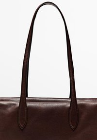 Borsa in pelle marrone con una texture liscia, manici allungati e un sottile dettaglio di cucitura lungo i bordi. Design semplice e strutturato.