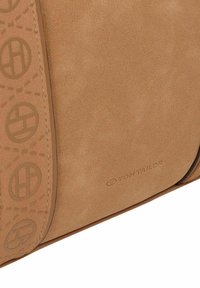 Bolso de hombro de ante marrón claro con correa de logo en relieve, que presenta una textura suave y detalles de costura, marcado con "TOM TAILOR."