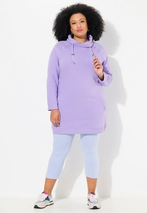 Felpa viola con collo a cowl, maniche lunghe e tasche laterali, abbinata a leggins blu chiaro e scarpe da ginnastica multicolori.