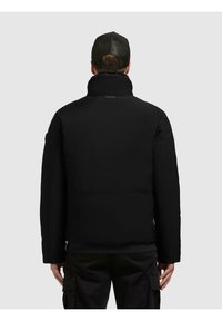 Black puffer jacket with high collar, insulated padding, and cuffed sleeves. Featured logo patch on the back. Worn with black cargo pants.