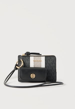Sort og gråt Michael Kors håndledspung med guld logoemblem, frontlomme med klap og fastgjort læderrem på hvid baggrund.