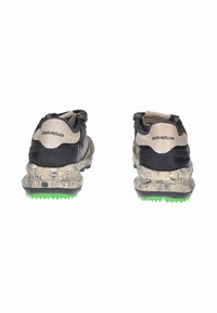 Scarpe da ginnastica nere e beige con suola texturizzata e marmorizzata e accenti verdi. Presentano un colletto imbottito e dettagli in rete. Logo "SATORISAN" visibile.