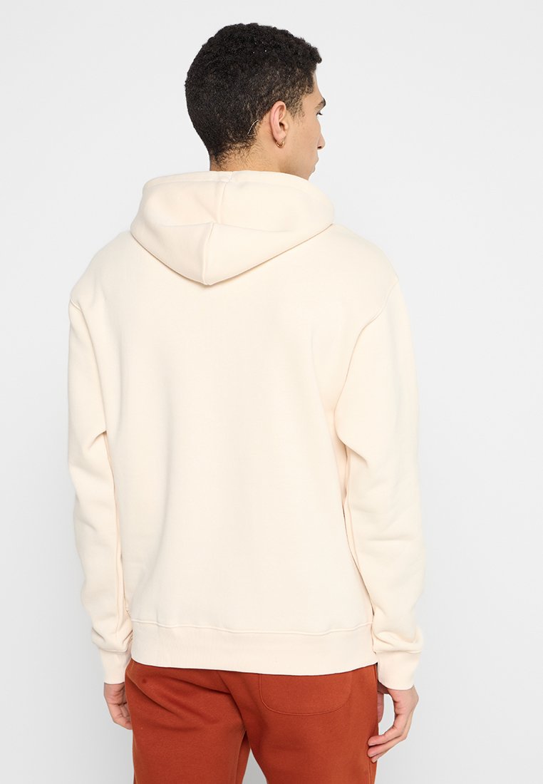 Sweatshirt à capuche de couleur crème, fabriqué dans un matériau doux, avec une coupe décontractée et des poignets côtelés, affiché de dos.