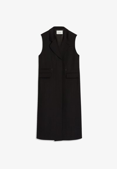 Camisola longa preta sem mangas com lapela recortada, botões frontais e dois bolsos laterais, feita de um tecido suave. Detalhes de design minimalista.