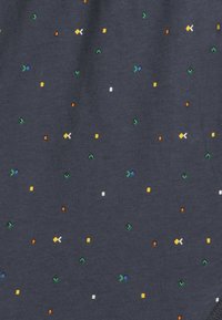 Granatowa tkanina o teksturowanym wzorze, z siatką małych, wielokolorowych kształtów geometrycznych w odcieniach zieleni, pomarańczu, żółci, niebieskiego i bieli.