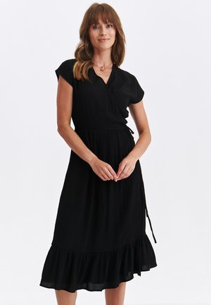 Czarna sukienka w stylu kopertowym z krótkimi rękawami, teksturowany materiał, dopasowana talia i rozkloszowany dół z falbaną na końcu.