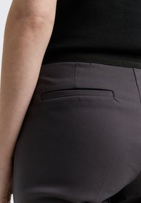 Gray trousers with a smooth texture, featuring a back pocket and a black waistband. The fabric appears lightweight and fitted.