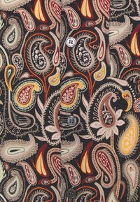 Flerfärgat paisleymönstrat tyg med intrikata mönster i rött, gult, grönt och gräddvitt på en mörk bakgrund med grå knappar.