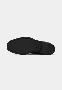 Semelle de chaussure en caoutchouc noir avec une texture lisse, une forme arrondie et un motif de semelle minimal. Présente un léger arc et un détail de logo en relief.