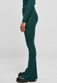 Geribbelde groene ensemble met een getailleerd ontwerp, uitlopende broekspijpen en een hoge taille. Gecombineerd met chunky zwarte plateau-schoenen.