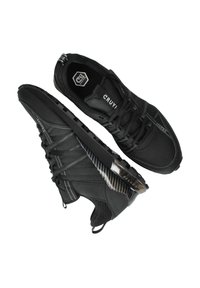 Zwarte sport schoenen met een bovenwerk van mesh, getextureerde accenten en een contrasterend carbonfiber detail aan de zijkant. Vetersluiting en gewatteerde kraag.