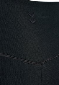 Close-up van zwart textuurstof met verhoogd chevronsteekdetail en een naad die een V-vorm vormt.