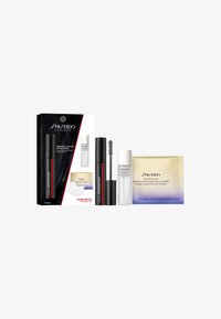 Un ensemble de cosmétiques Shiseido comprenant un mascara noir avec des accents rouges, un flacon de sérum blanc et un emballage de masque pour les yeux doré et violet.