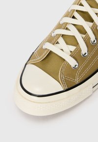 Canvas sneakers in olijfgroen met een crèmekleurige rubberen neus en zwarte accenten. Voorzien van off-white veters en metalen oogjes. Gekartelde witte zool.