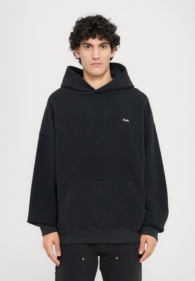 Czarna, oversize bluza z kapturem, wykonana z teksturowanej tkaniny, z przednią kieszenią, sznurkiem w kapturze oraz małym logo na klatce piersiowej.